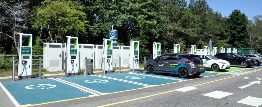 A row of turquoise parking bays with electric car charging points, and some cars