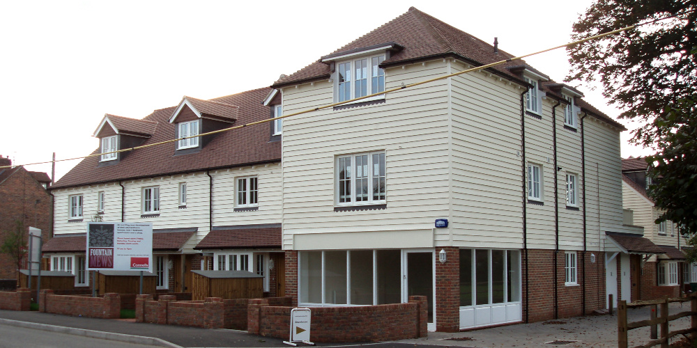 Modern three-storey building with cream-coloured walls above the ground floor and a sign reading: Fountain Mews