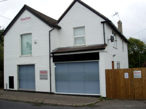 A white two-storey building with two gable roofs and three signs reading: West Park